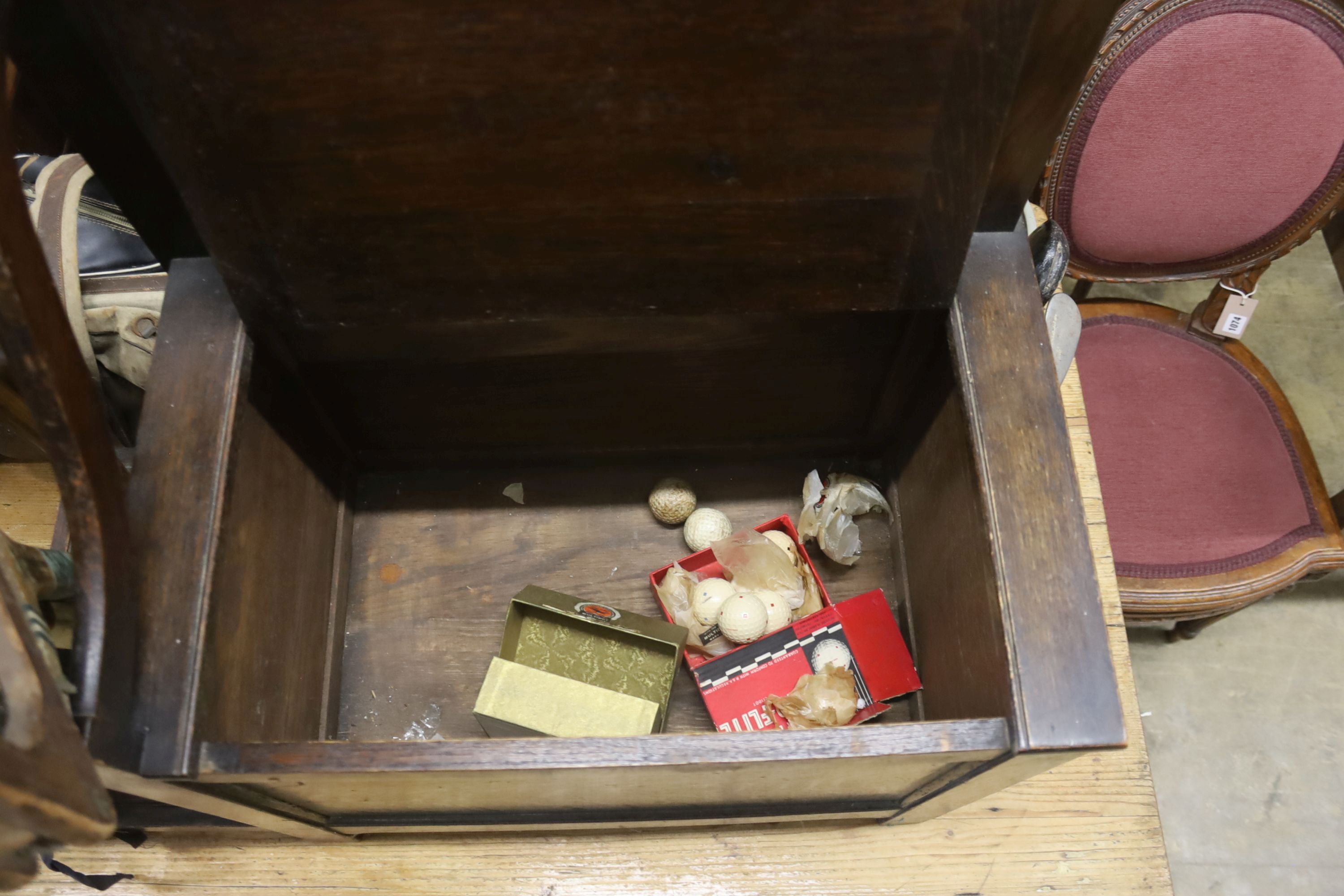 A 1920's oak hall seat together with a collection of vintage lacrosse sticks, golf clubs, etc.